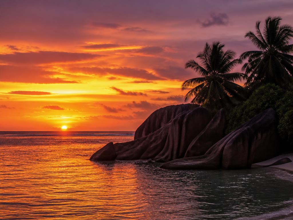 Sunset over granite rocks and palm trees in Seychelles
